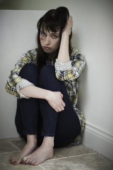 Female Victim Of Domestic Abuse Sitting On Floor