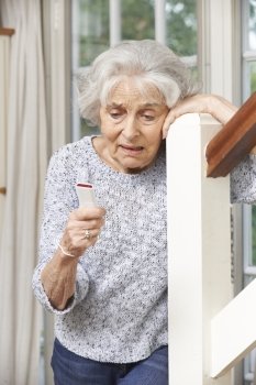 Unwell Senior Woman Using Personal Alarm At Home