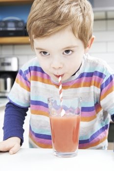 Young Boy Drinking Fruit Smoothie From Glass