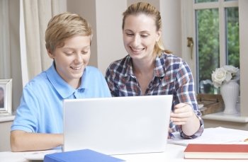 Female Home Tutor Helping Boy With Studies Using Laptop Computer