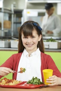 Female Pupil Sitting At Table In School Cafeteria Eating Healthy Lunch