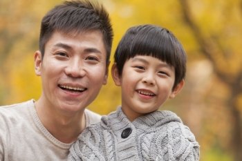 Father and son smiling in the park in autumn, close-up portrait