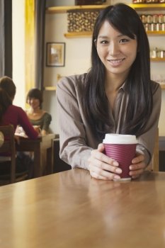 Portrait of young woman holding coffee cup in a coffee shop, Beijing