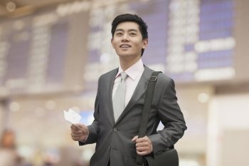 Young businessman holding ticket at the airport, Beijing, China