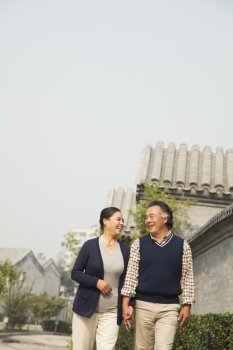 Senior couple going for a stroll in Beijing by traditional building, holding hands