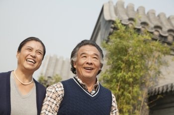 Happy senior couple walking outdoors by traditional building in Beijing