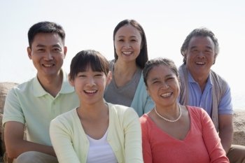 Portrait of smiling multigenerational family sitting on the rocks outdoors, China