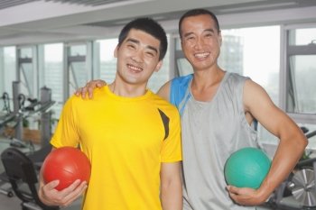 Two men holding balls in the gym