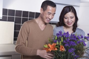 Mature Couple Looking at a Bouquet of Flowers in the Kitchen