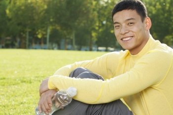 Young Athletic Man Sitting on the Grass in a Park