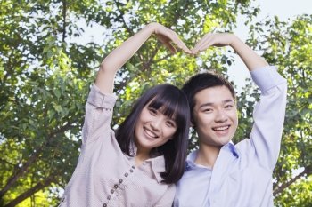 Young Couple Making a Heart Shape with Their Arms