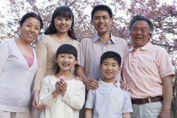 Portrait of a smiling multi-generational family amongst the cherry trees and enjoying the park in the springtime