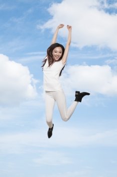Young smiling woman jumping in mid-air, sky and cloud background