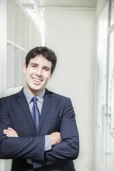 Portrait of young smiling businessman with arms crossed and looking into the camera