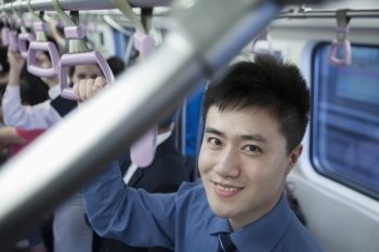 Portrait of smiling young businessman standing on the subway, looking at camera