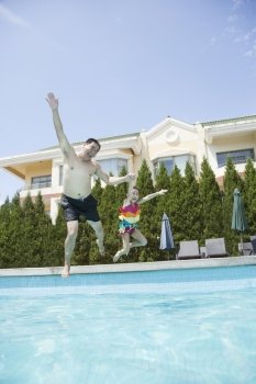 Father and daughter holding hands and jumping into the pool