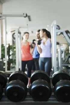 Three people lifting weights in the gym, focus on the weights