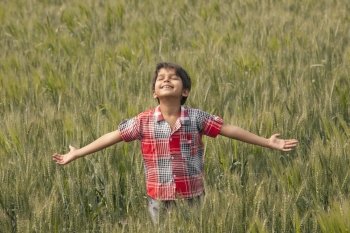Little toddler standing in wheat field with arms out 