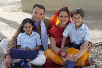 Portrait of a happy Indian family sitting on cot 