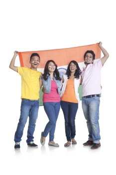 Full length portrait of happy young friends in casuals holding Indian flag over white background 