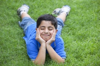 Smiling young boy lying on grass 