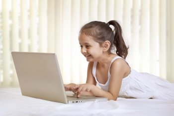Cute girl using laptop in bedroom 