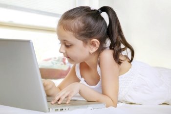 Girl using laptop while lying on bed 