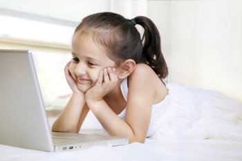 Smiling little girl looking at laptop screen 