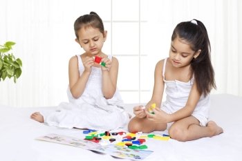 Girls solving puzzle while sitting on bed 