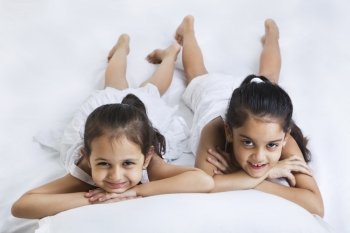 Portrait of cute little sisters lying on bed 