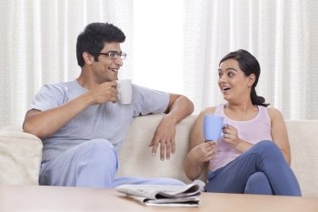 Cheerful young couple having coffee at home 