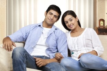 Portrait of happy young couple sitting on sofa 