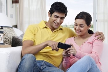 Young man pointing at mobile phone while watching something with girlfriend 