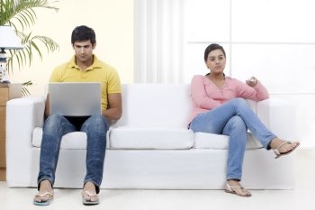 Full length of young couple sitting on sofa 