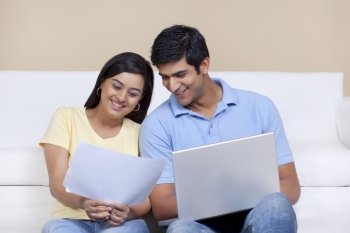 Woman holding paper while man using laptop 