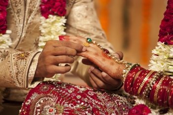 Close-up of a groom putting a wedding ring on a bride 