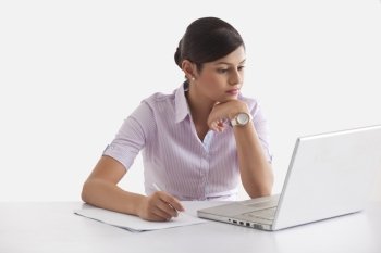 Confident young woman taking down notes from laptop 