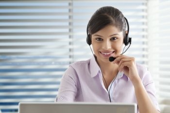 Young businesswoman using laptop in office , wearing headset 