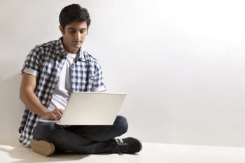 Young man sitting on floor with laptop 