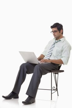 Male executive sitting on chair with laptop 