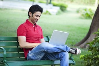 Young smiling man using laptop in lawn 