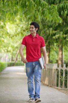 Smiling young man walking in park 