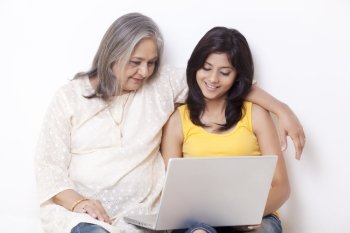 Teenage girl and grandmother using laptop 