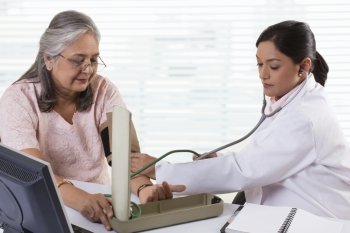 Female doctor checking patient’s blood pressure 