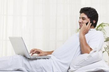 Smiling man having conversation while using laptop at home 
