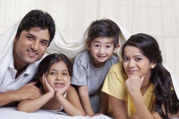 Portrait of smiling family lying in bed 