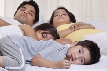 Portrait of boy holding chocolate while his family sleeping in the background 
