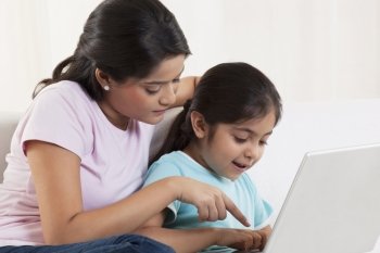 Mother assisting daughter using laptop 