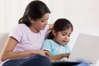 Mother and daughter using laptop at home 
