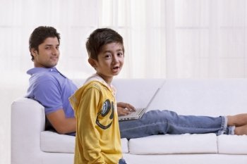 Portrait of little boy with father using laptop in the background 
